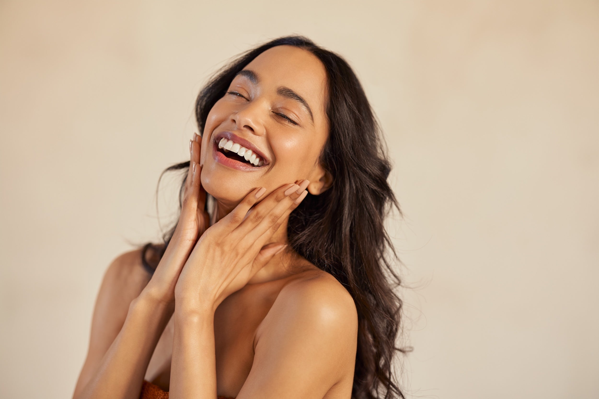 Beautiful laughing woman touching her skin with joy